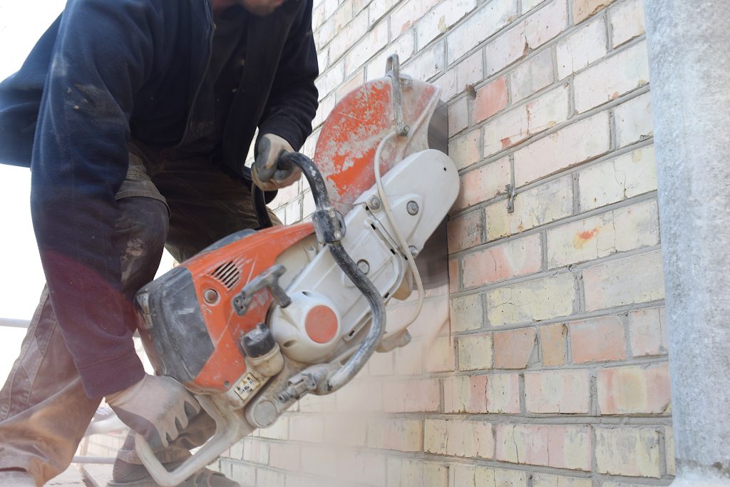 Cutting a hole in the wall using a cutter.