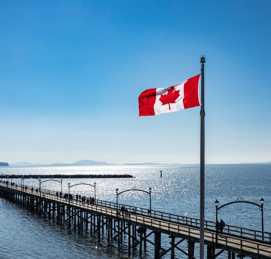 White Rock city pier in the dusk with flying Flag of Canada, British Columbia, Canada.